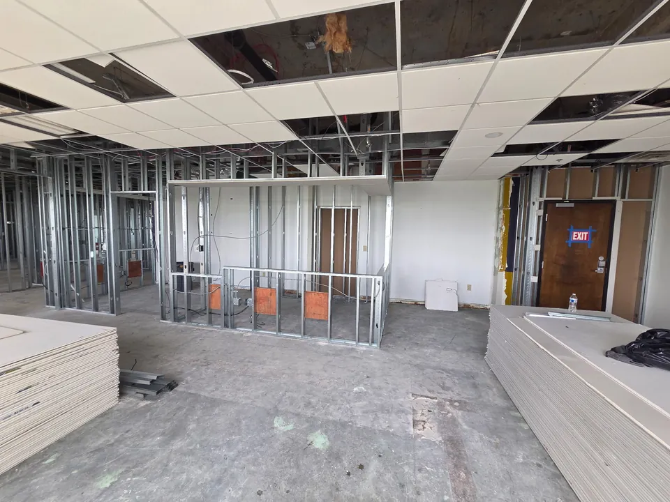 Reception area during construction with metal stud framing and drywall staged on site